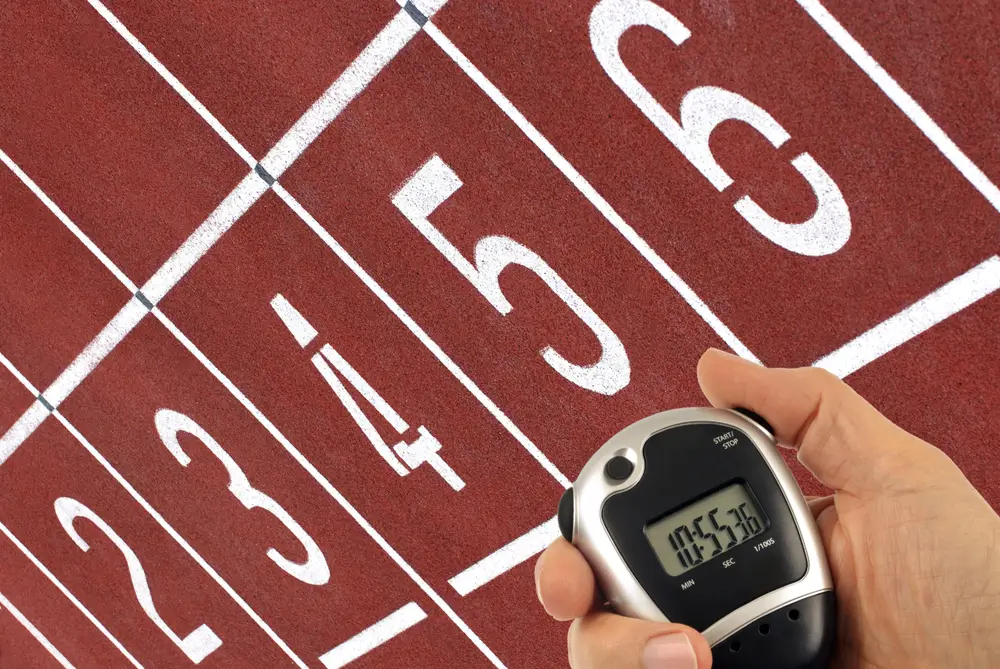 Chronomètre, cônes de balisage et feuille de barème posés sur une piste d'athlétisme pour un entraînement militaire