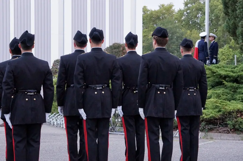 Élèves-officiers en uniforme de parade alignés au garde-à-vous lors de leur formation à l'académie militaire.