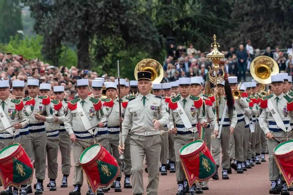 Musiciens de la Légion étrangère en képi blanc défilant avec tambours lors d'une cérémonie officielle.