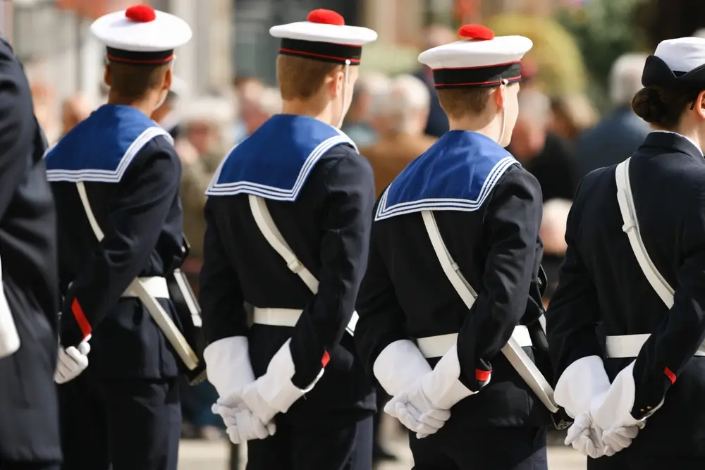 Marins français en tenue de cérémonie, vus de dos avec leur pompon rouge lors d'une cérémonie militaire française.