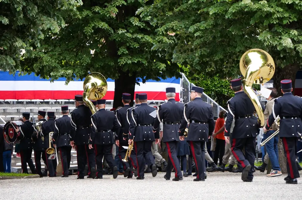 Musiciens militaires français en uniforme marchant avec leurs instruments pour jouer une partition de musique militaire.