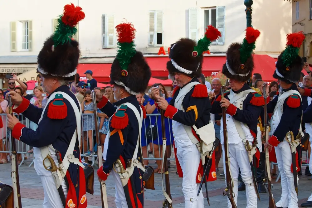 Soldats de l'infanterie révolutionnaire en costume historique avec bonnets à poil à plumes, armés de fusils d'époque.