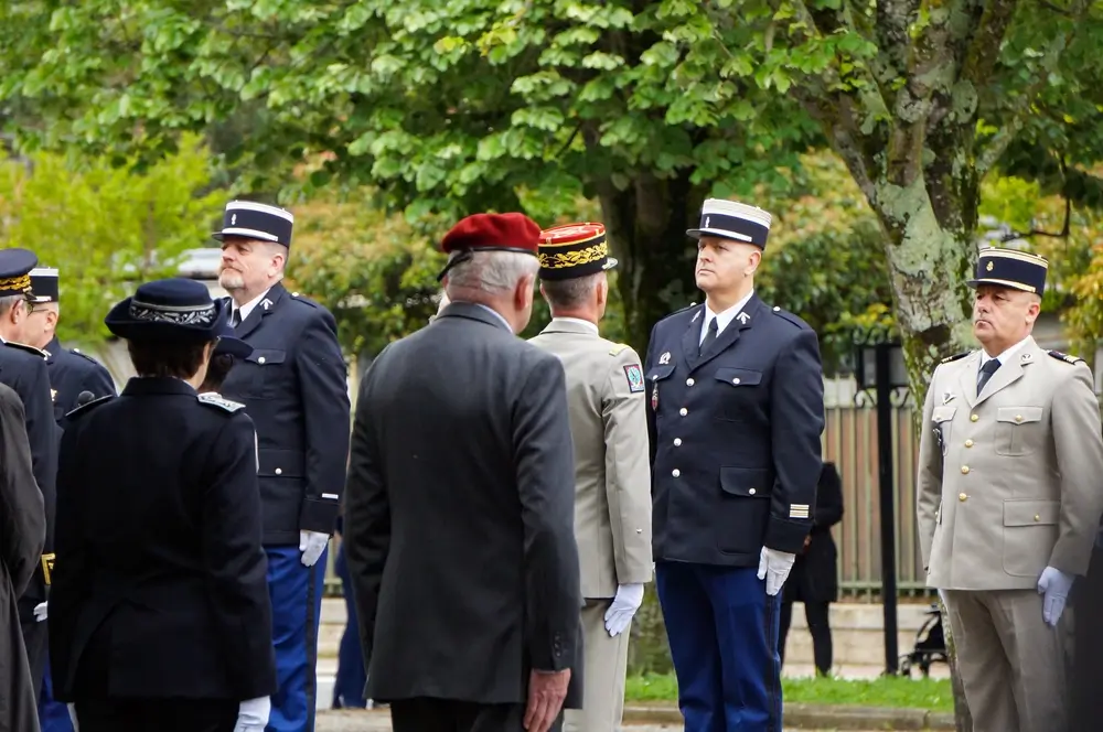 Officiers militaires en uniforme de cérémonie réunis en extérieur lors d’une séance de briefing de commandement.