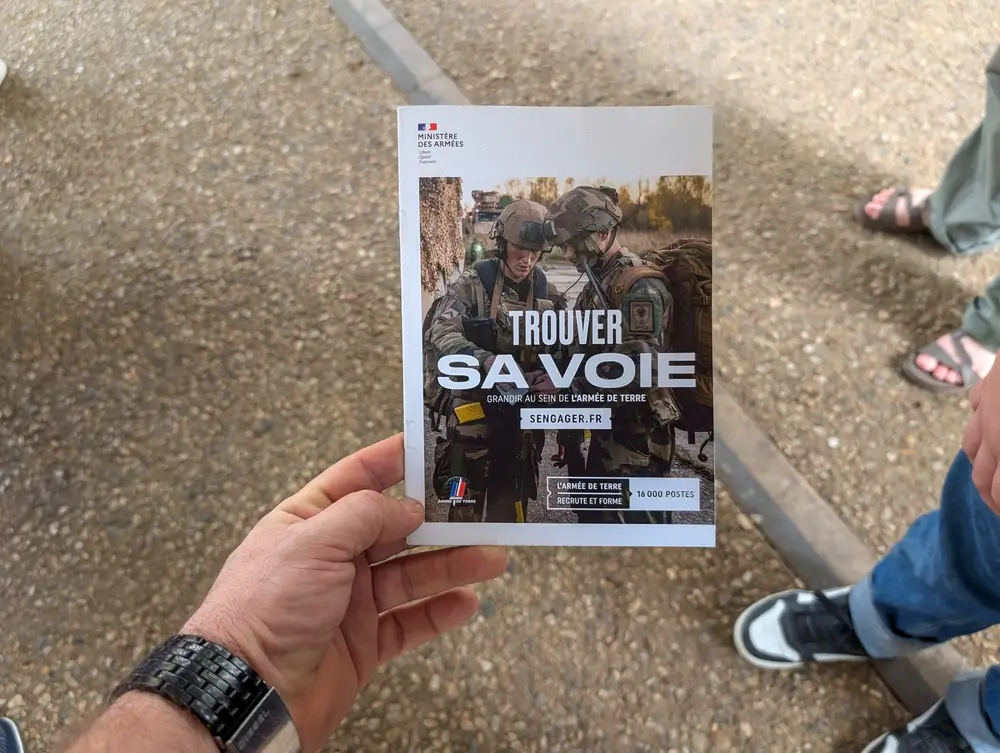 Candidat civil tenant une brochure de recrutement de l'Armée de Terre pour s'informer sur la préparation militaire.