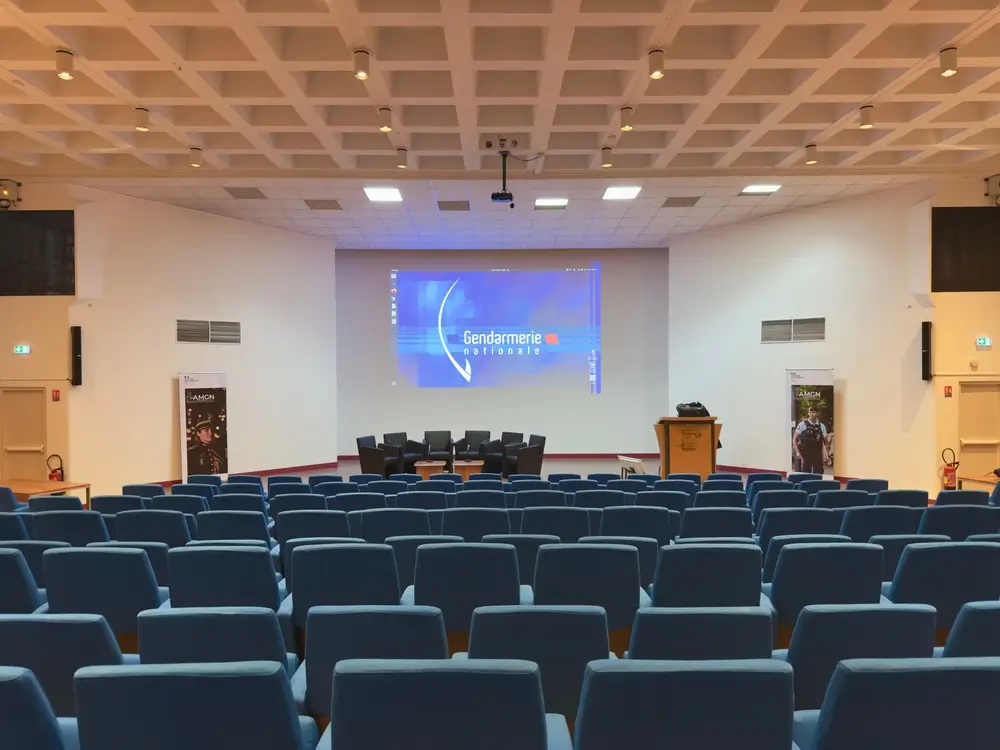 Amphithéâtre vide avec logo de la Gendarmerie nationale, prêt pour une cérémonie de remise de grades d'officiers.