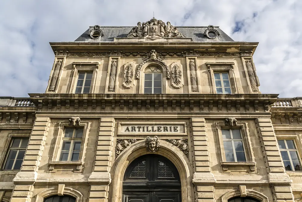 Façade sculptée d'un bâtiment de l'artillerie, emblème de l'armée et de la défense française.