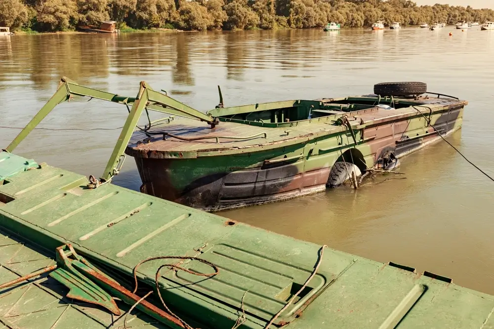 Véhicule du génie militaire installant un ponton flottant sur une rivière pour une opération de franchissement.