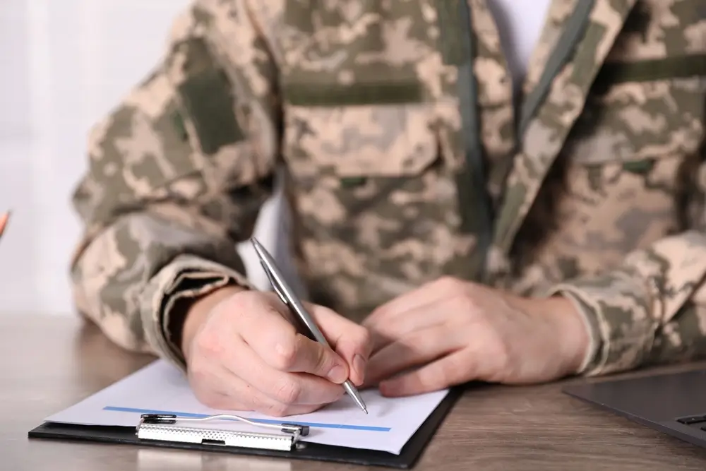 Candidat en treillis militaire passant un test écrit lors du recrutement dans un centre de sélection de l'armée.