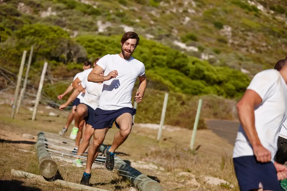 Homme en plein effort sur un parcours d'obstacles, s'entraînant pour réussir son test navette de course.